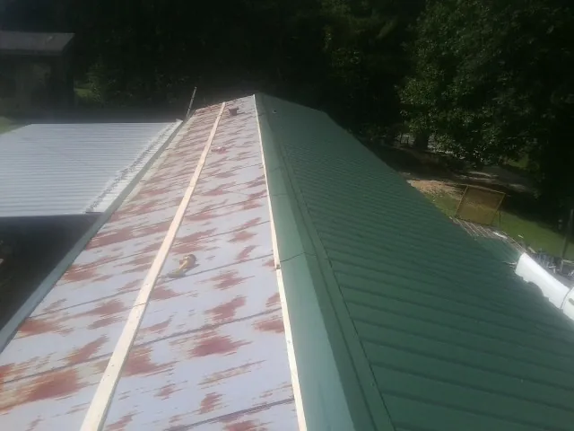 Old rusted panels beside newly installed green metal roofing — Wind Damage Roof Repair by Roofing Brothers in Hopedale