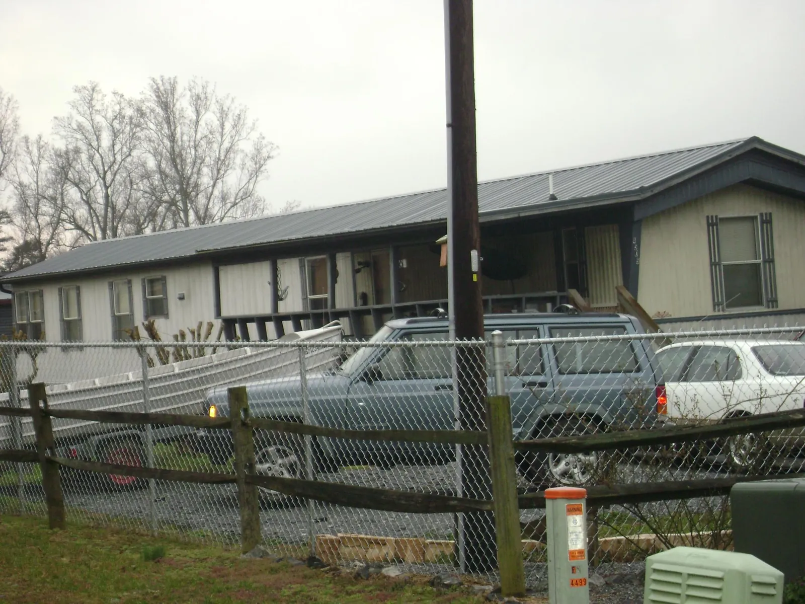 Dark metal roof on a long single story building behind a chain link fence in Hopedale