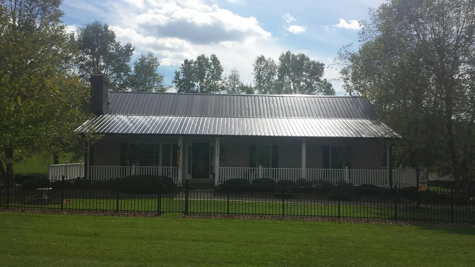 Gray metal roof on a brick ranch with a full width front porch — Gutter Guard Installation work by our crew in Hopedale